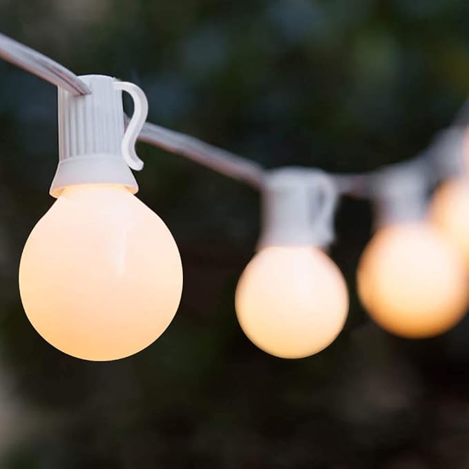 frosted globe outdoor string lights - white frosted globe bulbs hanging on a black wire in a garden setting in wholesale